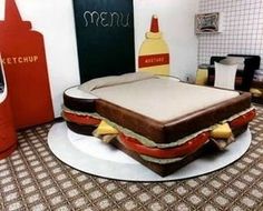 a giant sandwich cake sitting on top of a white plate in front of a blackboard