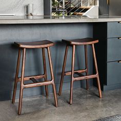 two wooden stools sitting in front of a counter