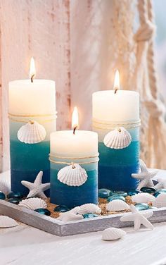 three candles with seashells and starfish on a tray