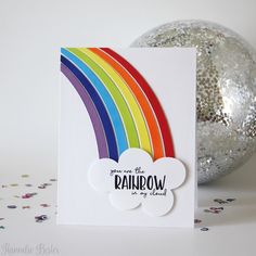 a card with a rainbow on it and confetti scattered around the card, next to a disco ball