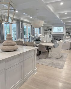 a large open concept kitchen and living room area with white cabinets, marble counter tops, and an island in the middle