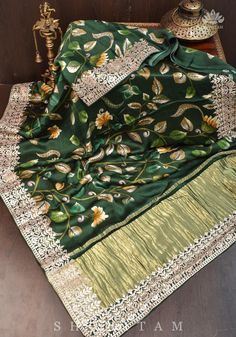 This Gajji Silk Saree by Shobitam is sure to add a touch of elegance to any special occasion. It features a stunning floral digital print and Gotta Patti borders with crushed zari palla, a traditional crafting technique from Rajasthan. Soft and lustrous, it comes with falls and pico done and an unstitched blouse fabric included. Elevate your look with this beautiful saree. Note: Colors that show up on your screen may vary slightly from the actual product due to variations in settings. Also, the Tussar Silk Fabric With Zari Work For Celebration, Celebration Tussar Silk Fabric With Zari Embroidery, Unstitched Dola Silk Suit With Zari Work For Celebration, Green Shawl With Resham Embroidery In Traditional Drape, Silk Unstitched Suit With Zari Work For Celebration, Celebration Raw Silk Unstitched Suit With Zari Work, Raw Silk Unstitched Suit With Zari Work For Celebration, Elegant Green Unstitched Suit With Cutdana, Silk Unstitched Suit With Cutdana For Celebration