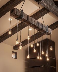 a bunch of light bulbs hanging from a beam in a room with exposed beams and wooden beams