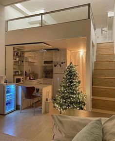 a living room filled with furniture and a christmas tree in front of a kitchen area