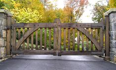 an open wooden gate with stone walls and trees in the background