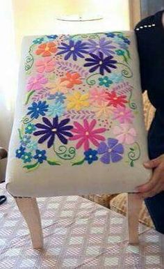 a woman holding up a pillow with flowers on it