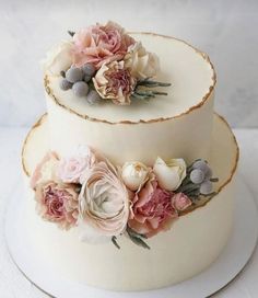 two tiered wedding cake decorated with flowers on white plate, ready to be cut