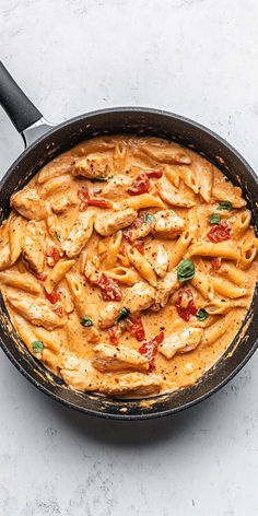 a skillet filled with pasta and chicken