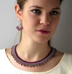 a woman wearing a necklace and earrings with pink beads on her neck is looking at the camera