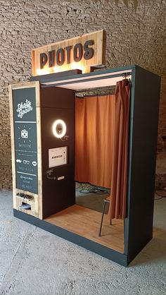 an old fashioned photo booth in the shape of a box with curtains and lights on it