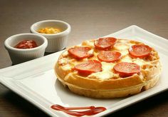 a white plate topped with a pizza covered in toppings next to two small bowls