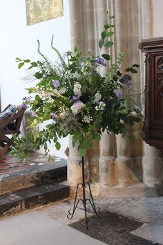 a bouquet of flowers sitting on top of a metal stand in front of a door