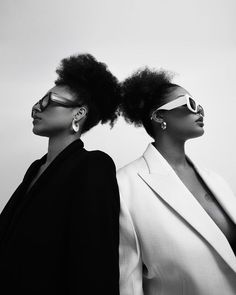 two black women with sunglasses on their heads, one wearing a white suit and the other in a black blazer