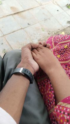 a man and woman holding hands while sitting on the ground with their arms folded together