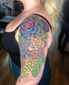 a woman with a colorful flower tattoo on her arm and shoulder, standing in a room