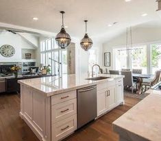 a large kitchen with an island in the middle and two pendant lights hanging from the ceiling