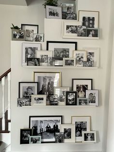 a bunch of pictures are hanging on the wall next to some stairs in a house