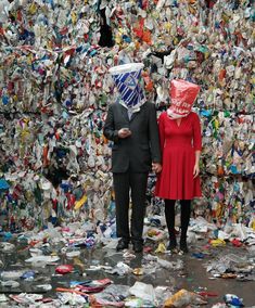 a man and woman standing next to each other in front of a pile of trash