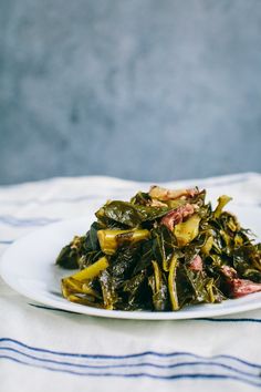 a white plate topped with collard greens on top of a blue and white table cloth