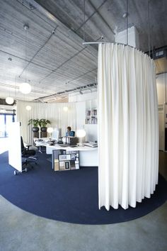 an office with white drapes hanging from the ceiling and blue carpeting on the floor