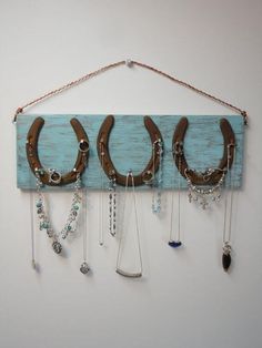 a wooden board with horseshoes hanging from it's sides and some necklaces attached to the hooks