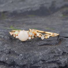 an opal and diamond ring sitting on top of a rock