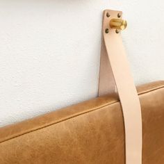 a brown leather bench with a white strip on the back and gold handles hanging from it's side