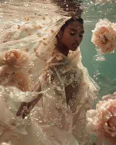 a woman wearing a wedding dress under water with flowers floating around her and in the air