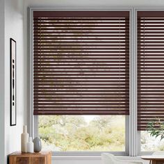 a living room with two large windows covered in brown blinds and a white chair next to the window