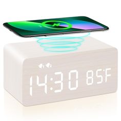 an alarm clock with a cell phone sitting on it's back and the time displayed