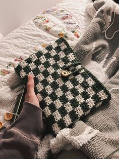 a person is laying on a bed holding a crocheted purse