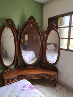 three mirrors sitting on top of a wooden dresser next to a bed in a room