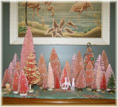 pink christmas trees with flamingos and other decorations on a table in front of a painting