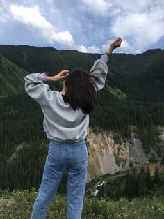 a woman standing on top of a lush green hillside