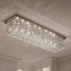 a large rectangular crystal chandelier hanging from the ceiling in a room with white walls