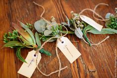 the flowers are tied up with twine and tags on them, sitting on a wooden table