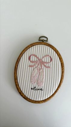 a hand embroidered wall hanging with a bow and word love on striped fabric in a wooden frame