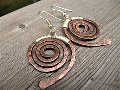 two pairs of copper earrings on top of a wooden table