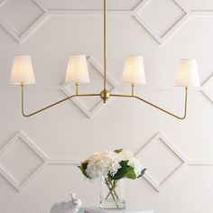 a vase with white flowers on top of a table next to a wall mounted lamp