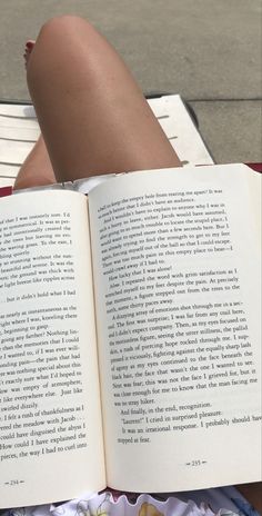 a person laying down reading a book with their legs crossed and her feet propped up