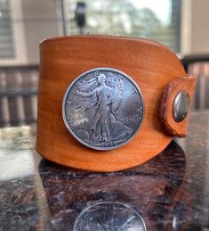 "Leather Boho Cuff with Lady Liberty Concho Sable brown-stained leather  Signature asymmetrical cufff All stains will be slightly different but similar to the colors displayed.  Each piece is unique in exact color pattern.  Perfect to stack with my other bracelets.  Fits a 7\" wrist perfectly Link to Tenile Creations LLC storefront: www.etsy.com/shop/TenileCreations  HOW TO MEASURE YOUR WRIST For at home wrist measurements: Measure your wrist circumference just above the bone. Feel your wrist to locate the knobby bones on either side of your arm and place your string on the side just above it. Wrap the string around your wrist until it's snug and mark where it overlaps the end. Straighten out the string and hold it against a ruler to find your measurement. Write the measurement down so you Leather Concho Cuff Bracelet, Leather Cuff Bracelet With Concho, Vintage Leather Strap Cuff Bracelet, Vintage Brown Leather Cuff Bracelet, Vintage Brown Hand Tooled Cuff Bracelet, Vintage Brown Hand-tooled Cuff Bracelet, Vintage Brown Cuff Bracelet, Vintage Leather Cuff Bracelet In Distressed Brown, Vintage Hand-tooled Brown Cuff Bracelet