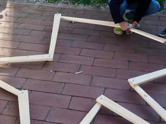 two people are working on some wooden frames that have been cut into squares and placed on the ground