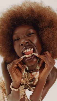 a woman with an afro has her mouth open and is holding something in front of her face