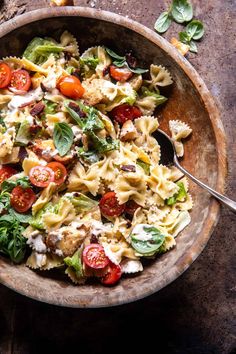 a wooden bowl filled with pasta salad on top of a table