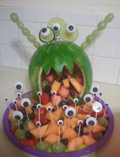 a purple bowl filled with lots of fruit covered in googly eyes