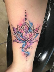 a woman's foot with a watercolor lotus tattoo on the left side of her leg