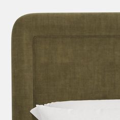 a bed with a green headboard and white sheets on it's bottom half