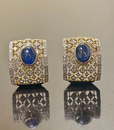 DeKara Designs Collection Metal- 18K White Gold, .750. 15.50 Grams. Stones- 2 Genuine Cabochon Oval Ceylon Blue Sapphires 5.02 Carats, 168 Round Diamonds F-G Color SI2 Clarity 2 Carats. One of a kind entirely handmade, Art Deco 18K Yellow Gold Sri Lanka Ceylon Cabochon Cut Blue Sapphire and Pave Set Diamond Art Deco Inspired One of a Kind Earrings. Each earring has an amazing oval cabochon blue sapphire that is professionally and uniquely bezel/burnish set. There are 79 round pave set diamonds o Oval Sapphire Earrings With 17 Jewels, Luxury Oval Earrings For Formal Occasions, Exquisite Cabochon Earrings For Formal Occasions, Exquisite Formal Cabochon Earrings, Luxury Diamond Cabochon Earrings, Luxury Diamond Earrings With Cabochon, Luxury Cabochon Earrings For Wedding, Luxury Sapphire Earrings For Formal Occasions, Elegant Blue Hand Set Earrings