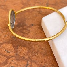 24KT yellow gold-plated + sterling silver replica Roman coin bangle with diamond. Double-sided silver coin set with textured, matte finish to the gold bangle! Length: 7" approx. Diameter: 60mm Band width: 2mm Weight: 11.80 grams (1) .01 CT natural, round diamond 21mm round replica coin Hook style clasp 925 sterling silver purity with 24KT gold plating Adjustable Tarnish Resistant Bangle, Adjustable Etched Round Bangle, Adjustable Etched Bangle, Adjustable Engraved Coin Jewelry, Engraved Adjustable Coin Jewelry, Roman Coins, Diamond Bangles Bracelet, Coin Set, 24kt Gold