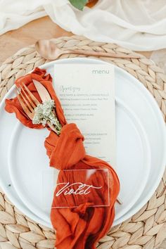 a place setting with napkins, forks and a menu on a wicker plate